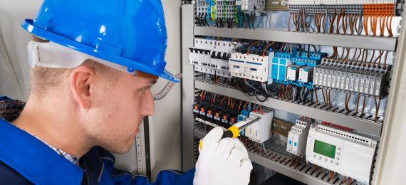 Male Electrician Examining Fusebox Male Electrician Working On Fusebox With Screwdriver