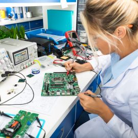 Female electronic engineer testing computer motherboard in laboratory Leiharbeiter Elektriker